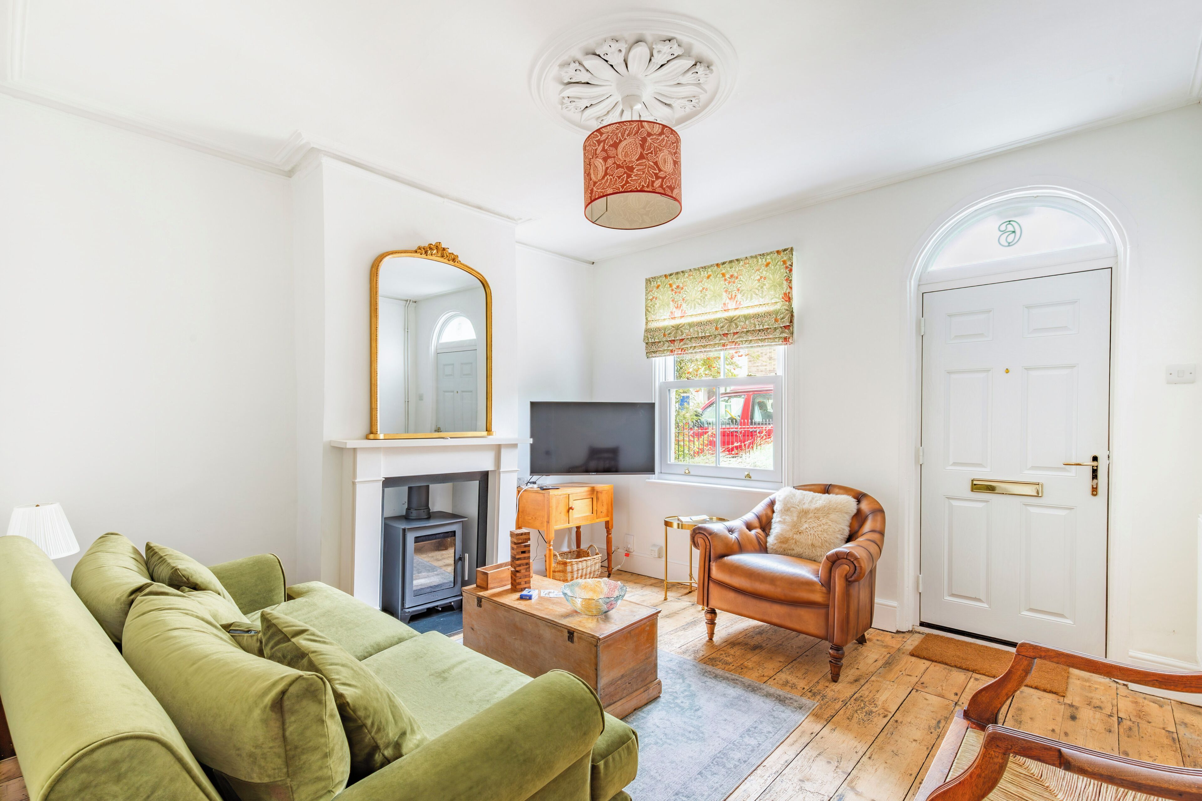 A living room with a sofa, a fireplace, a television, and a door.