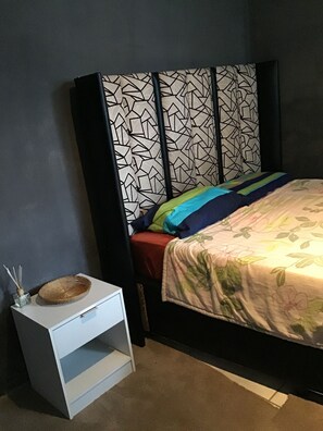 A bedroom with a bed, a bedside table, and a wall unit.