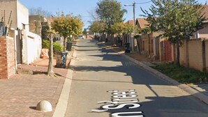 A residential street with houses on both sides, a clear sky, and a street sign indicating 'San Juan Street'.
