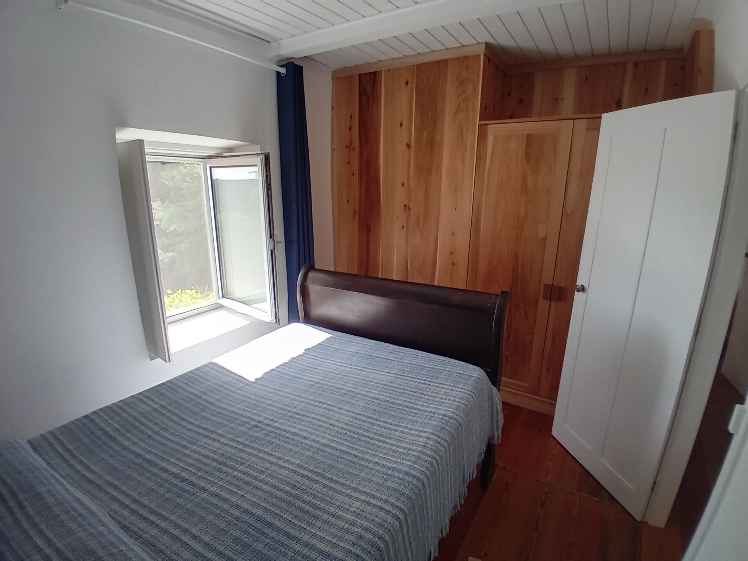 Et soveværelse med seng, garderobe og vindue.