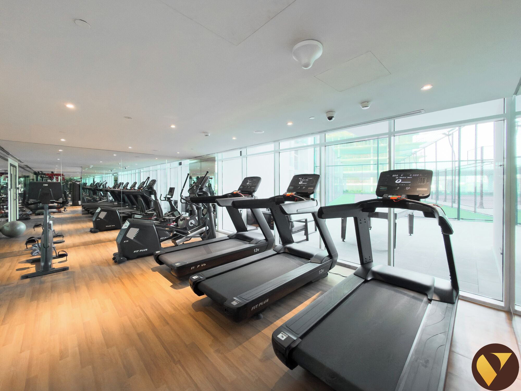 Een sportschool met meerdere loopbanden, hometrainers en diverse fitnessapparaten.