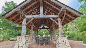 A covered outdoor seating area with stone pillars, tables, and chairs.