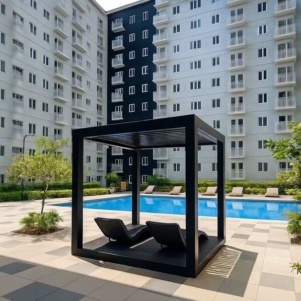 A modern outdoor pool area with a glass enclosure and lounge chairs. - Cosy Family staycation Casa De Nordeka Felix (Cainta)
