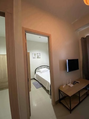 A hotel room with a bed, a TV mounted on the wall, and a small table with a remote control. - Cosy Family staycation Casa De Nordeka Felix (Cainta)