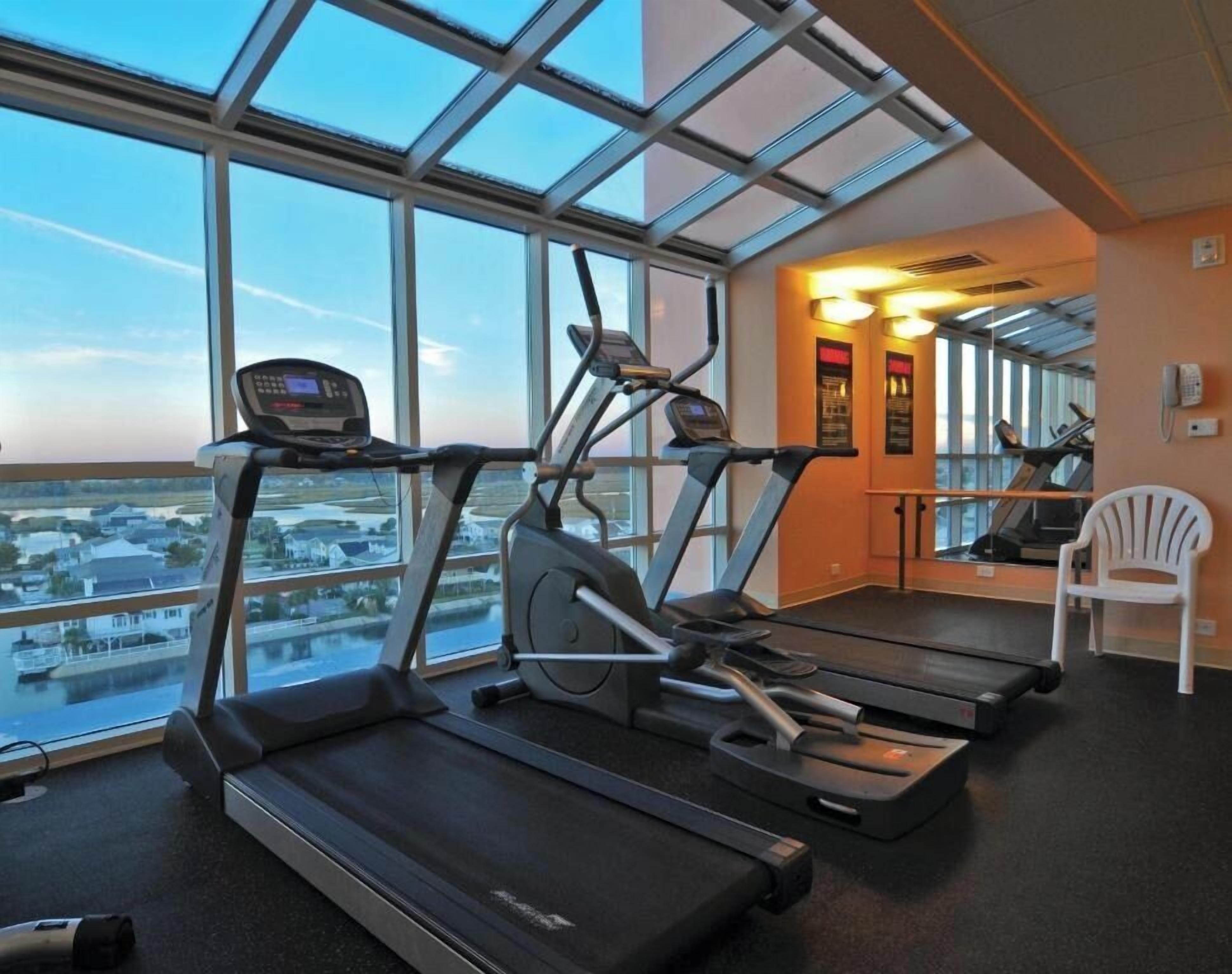 A gym with treadmills, a rowing machine, and a chair.