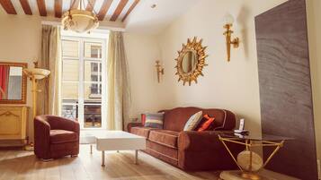 Een woonkamer met een bruine bank, een witte salontafel, een rode fauteuil, een grote spiegel en een schilderij aan de muur.