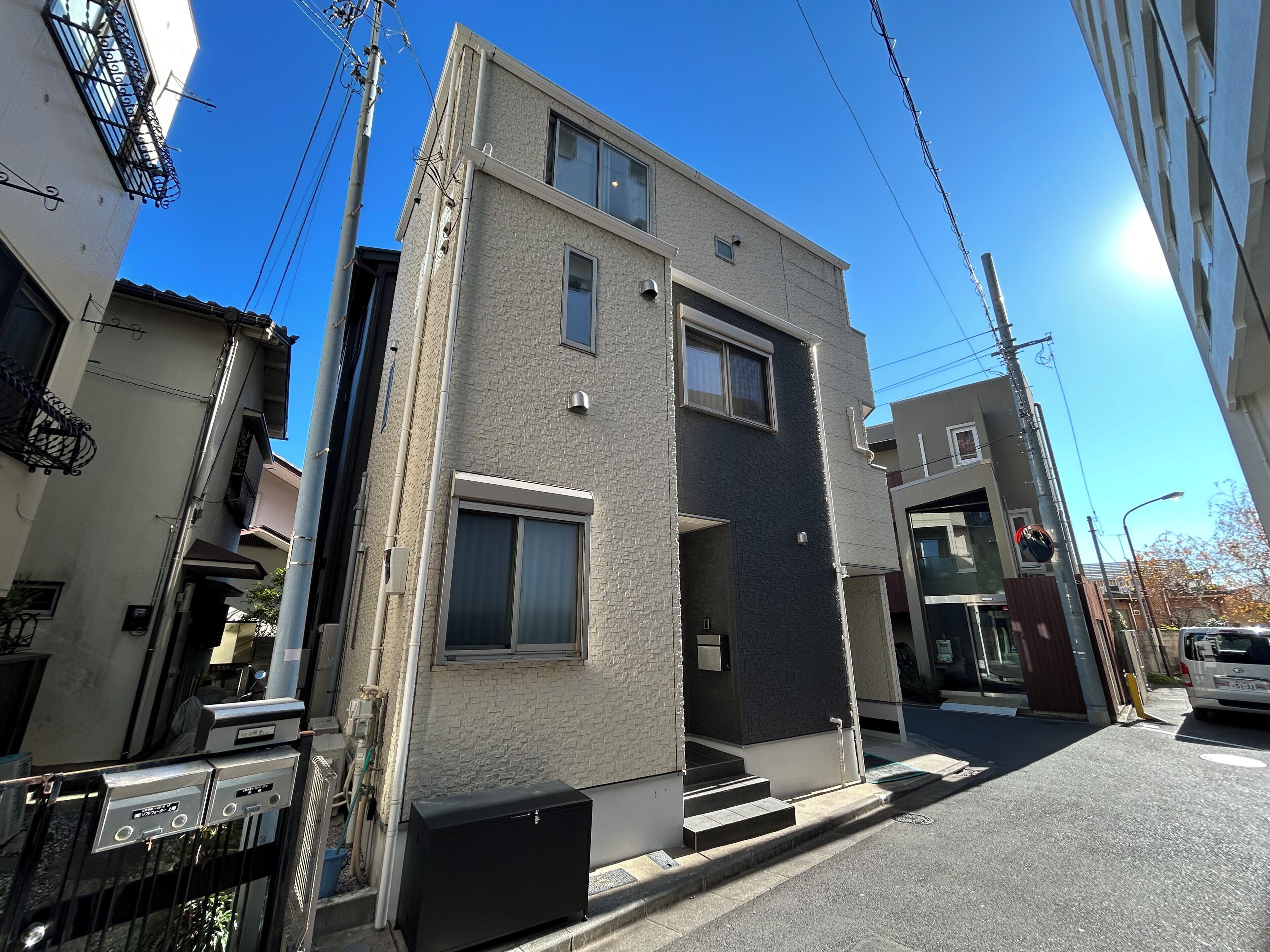 A two-story residential building with a modern design, featuring a flat roof, large windows, and a visible entrance.