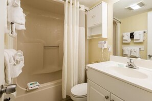 Un baño con bañera, inodoro, lavabo y toallero.