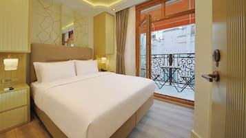 A hotel room with a large bed, bedside tables, a nightstand, a window with a view of the outside, and a balcony with a wrought iron railing.