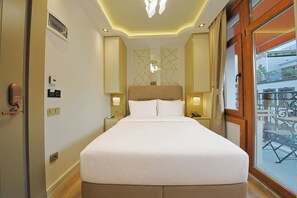 A hotel room with a large bed, bedside lamps, a nightstand, a thermostat, and a view of the outside. - Colombo Hotel (İstanbul)