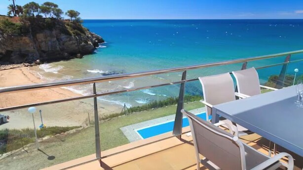 Un balcone con vista sul mare, una piscina e mobili da esterno.