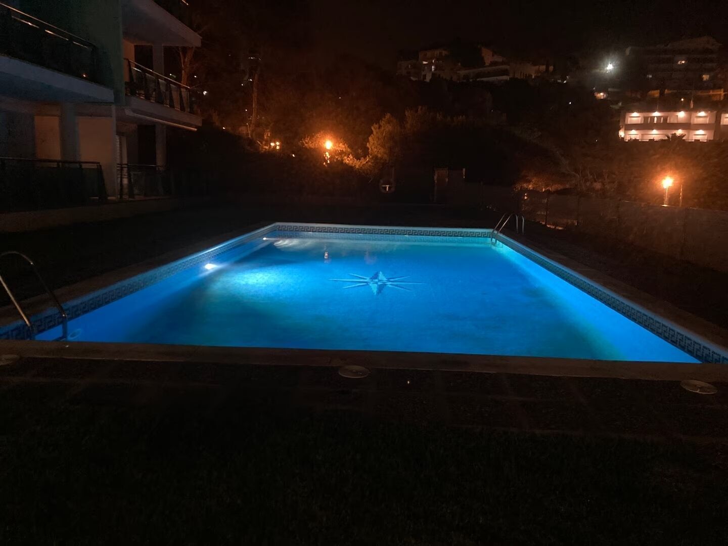 A rectangular swimming pool with a star-shaped design in the center, surrounded by a low brick wall.