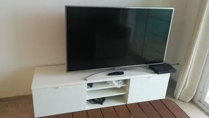 Una TV a schermo piatto su un mobile bianco contenitore, con un telecomando e un dispositivo nero sopra.