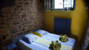 A single bed with striped bedding, a stone wall, a radiator, and a window with curtains. - Domaine de Ribière - Chambre #2, 2 Pers (Grospierres)
