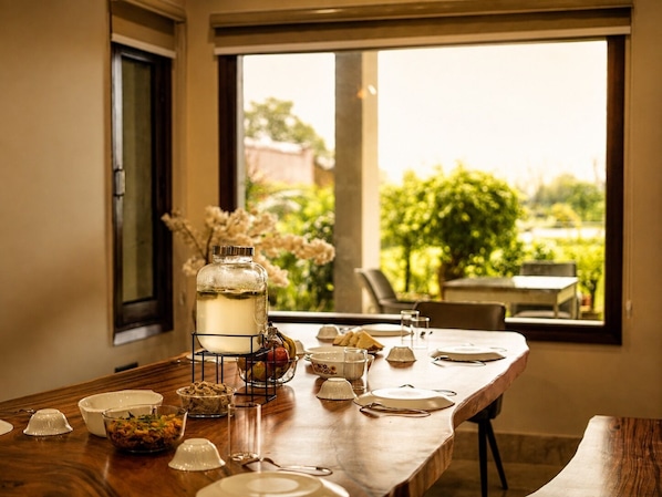 A dining table set with various dishes, a water dispenser, and a view of greenery outside.