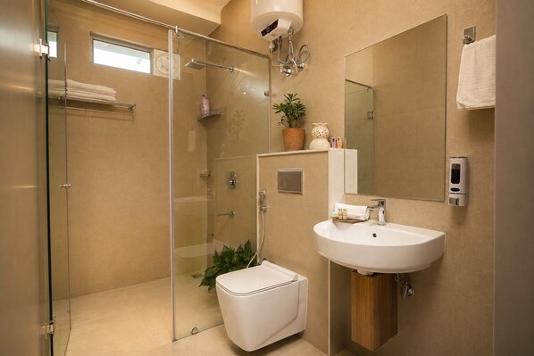 A modern bathroom with a glass shower enclosure, a white sink, and a mirror.
