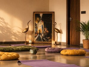A room with a large painting, two bird sculptures, and several yoga mats.