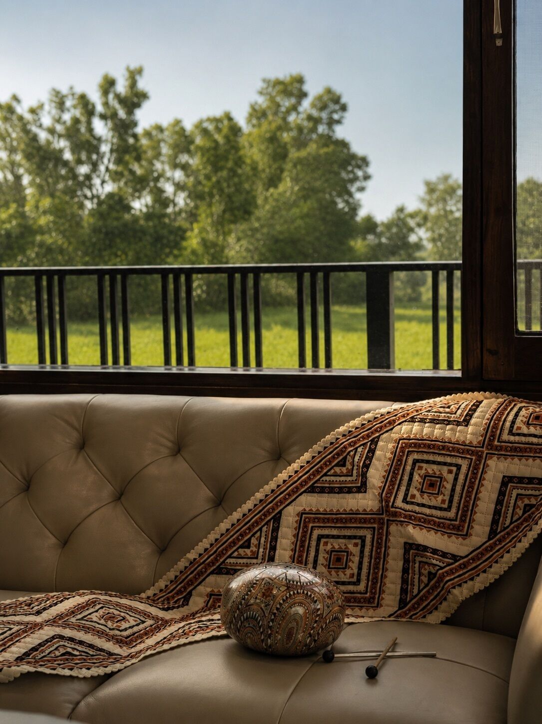 Un canapé en cuir agrémenté d’un plaid à motifs et d’un coussin décoratif.