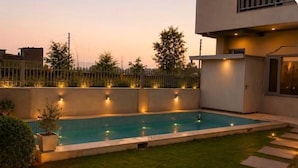 A rectangular swimming pool with a tiled edge, surrounded by a well-maintained lawn and a low fence.