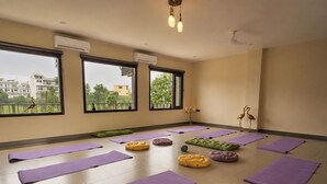 A yoga room with multiple mats, a green cushion, and a decorative bird statue.