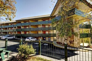 Un hotel a più piani con balconi, un'area di parcheggio e un pilastro in pietra.