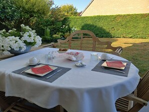An outdoor dining table set with white tablecloth, plates, cutlery, and a bowl of flowers. - Welcome to a haven of tranquility in Zuydcoote (Zuydcoote)