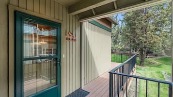 A wooden exterior with a green door, a welcome sign, and a covered porch with a metal railing.