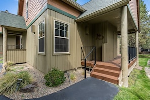 A two-story house with a covered porch, a front door, and a staircase leading to the entrance.