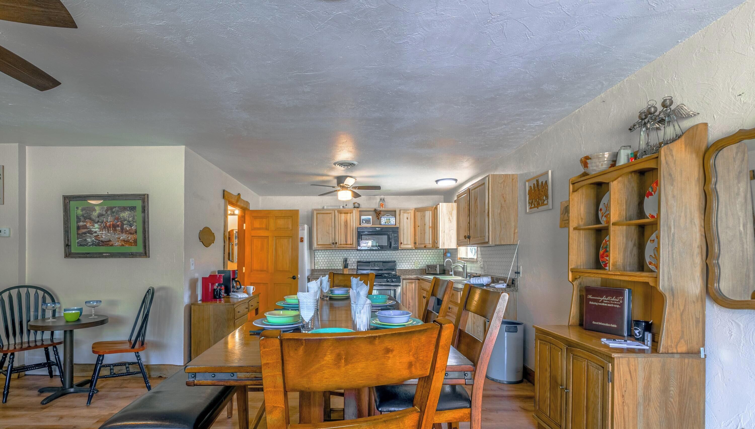 A dining area with a wooden table and chairs, a kitchen with wooden cabinets, and a ceiling fan.