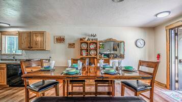Un comedor con una mesa de madera dispuesta para cuatro personas, rodeada de sillas de madera.