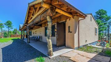 Una cabaña rústica con porche de madera, mobiliario exterior y puerta con picaporte de metal.