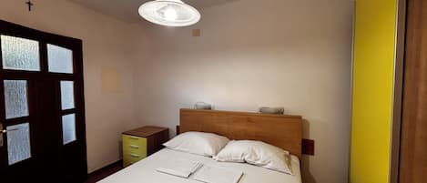 Un dormitorio con cama, mesita de noche y lámpara colgante.