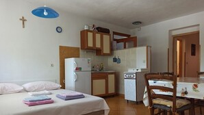 Una camera da letto con un letto, un angolo cottura e un'area pranzo con tavolo e sedie.