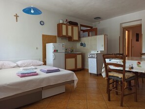 Ein Schlafzimmer mit einem Bett, einer kleinen Küchenzeile und einem Essbereich mit Tisch und Stühlen.