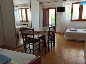 Ein Zimmer mit Esstisch, Stühlen, einem Bett und einem Fernseher.