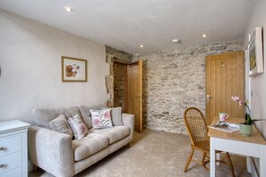 A cozy room with a sofa, a wooden chair, a desk, and a stone wall. - Billy Goats Gruff - Bakewell , Derbyshire (Bakewell)