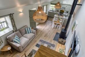 A spacious living area with a sofa, a dining table set for four, a kitchen with modern appliances, and a large window providing natural light. - Billy Goats Gruff - Bakewell , Derbyshire (Bakewell)