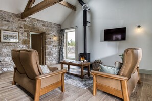 Un salón acogedor con pared de piedra, muebles de madera, chimenea y televisor.