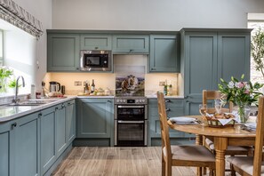 Una cocina moderna con armarios color turquesa, electrodomésticos de acero inoxidable y un comedor con una mesa y sillas de madera.