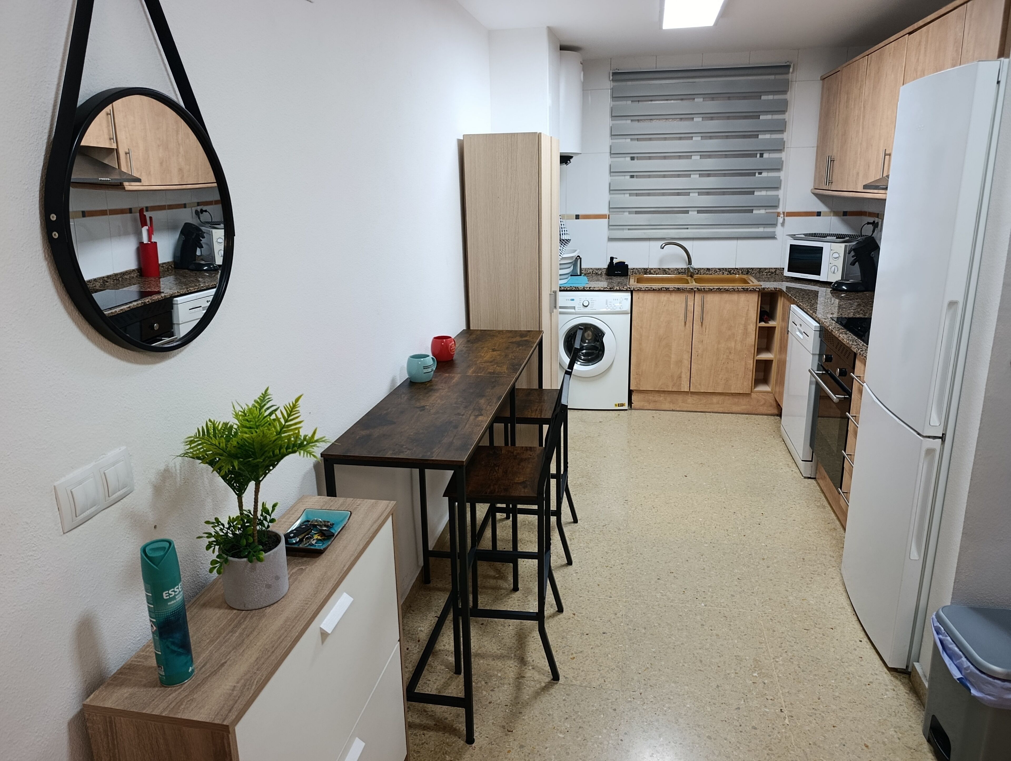 A compact kitchen with a washing machine, a microwave, and a refrigerator.