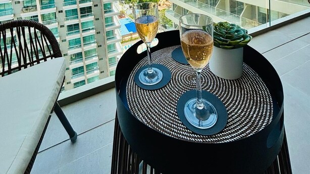 Ein Balkon mit Tisch, zwei Weingläsern und einem Blumentopf.