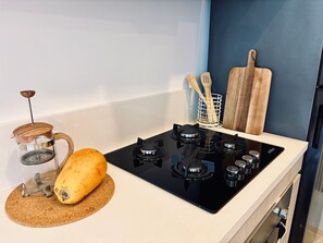 A kitchen with a stove, a wooden cutting board, a basket with wooden utensils, and a glass container with a metal lid. - Luxury Sky Retreat / Rooftop with Ocean View (Santa Marta City)