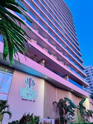 Een hoog hotel met een modern ontwerp, met meerdere balkons en een opvallend bord met 'RESERVA DEL MAR'.
