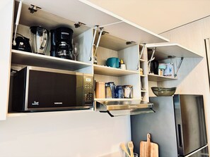 Una cucina con forno a microonde integrato, macchina del caffè e diversi utensili da cucina.