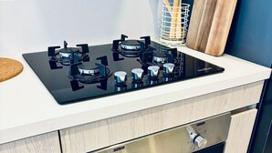 Una cocina moderna con estufa negra, utensilios de madera y tabla de cortar.