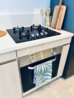Eine moderne Küche mit einem schwarzen Kochfeld, Holzkocherwerkzeugen und einem Schneidebrett.
