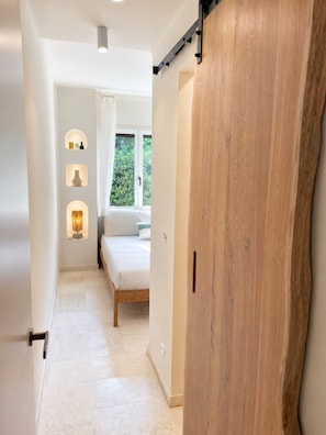 Ein Schlafzimmer mit einem Bett, einem Fenster und einem Holzschrank.