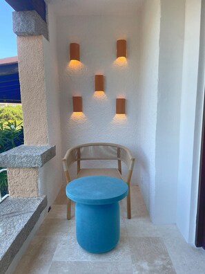 Eine gemütliche Ecke mit einem blauen runden Tisch, einem Korbstuhl und drei Wandleuchten.
