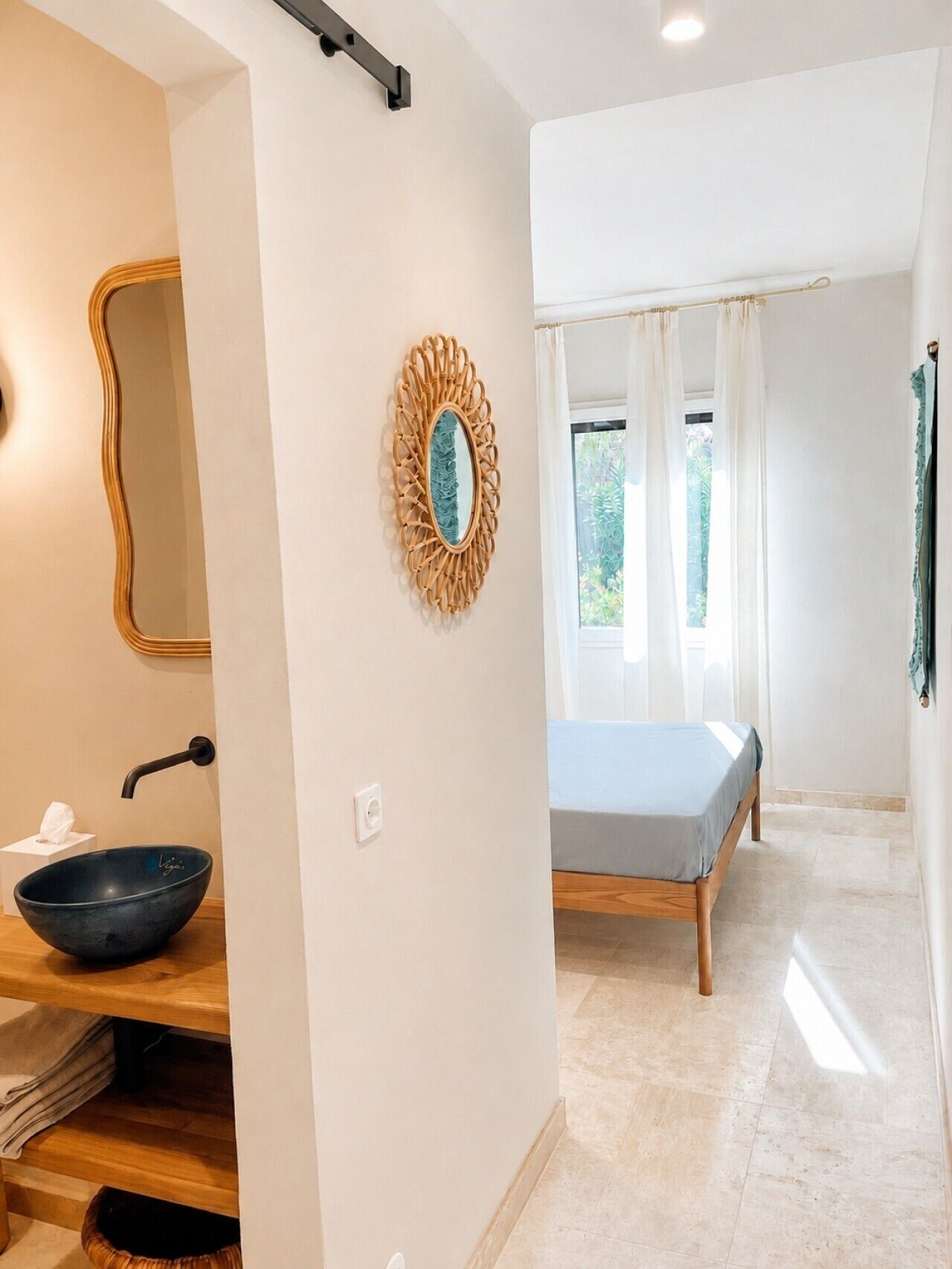 Un baño moderno con tocador de madera, un lavabo negro y un espejo.