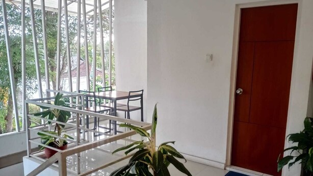 Un hall d’hôtel avec un comptoir d’accueil, un escalier et une porte rouge.